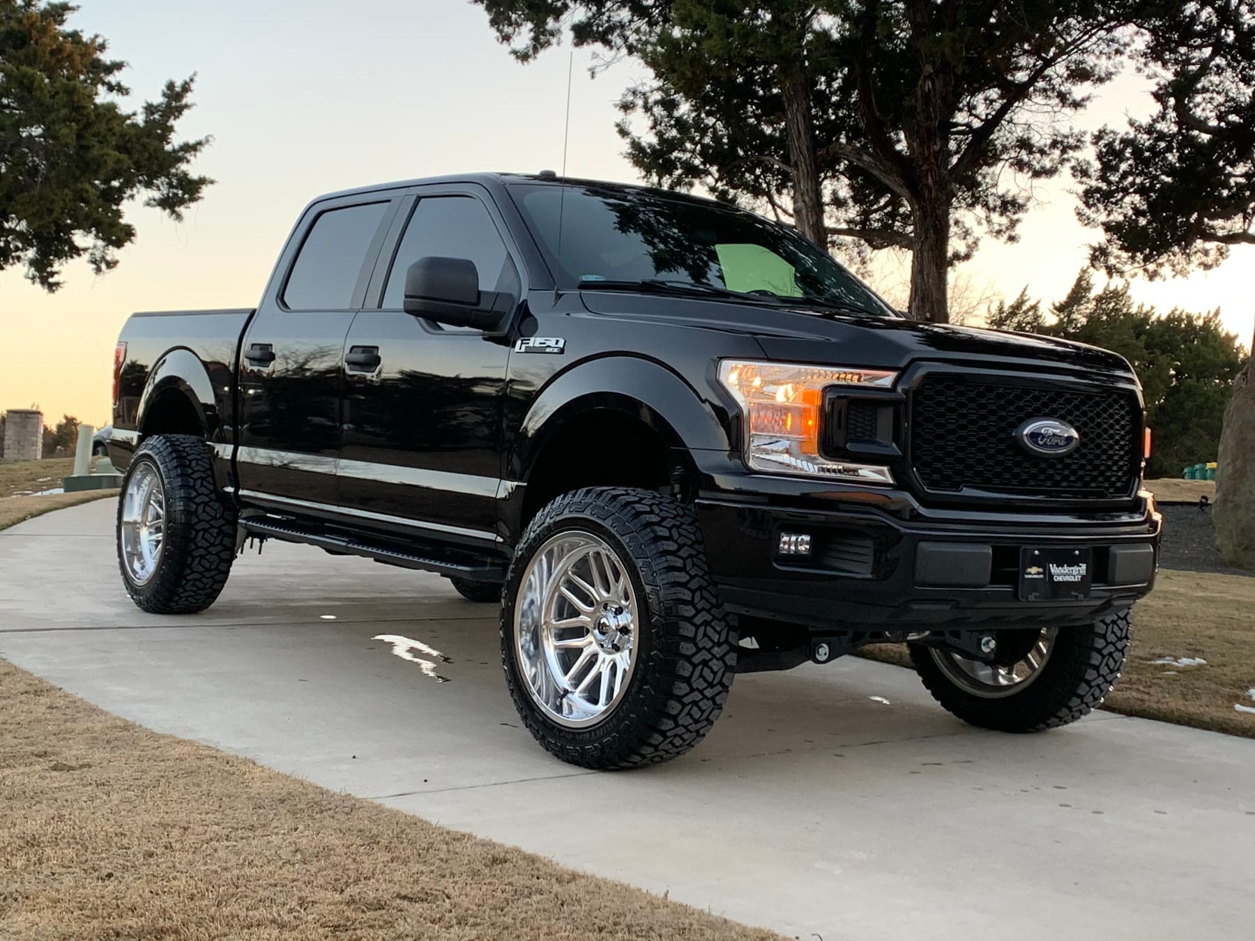Lifted black Ford F-150 with finished wheels and tires